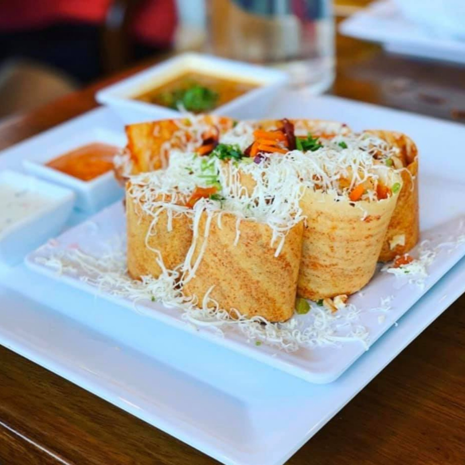 Four Honest Indian dosas, filled with vegetables and topped with shredded cheese, served with dipping sauces.